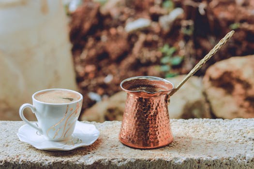 Discover the rich flavors of Turkish coffee served in a porcelain cup with a traditional copper cezve outdoors.